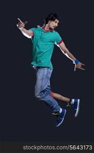 Young man in casual clothing dancing over black background