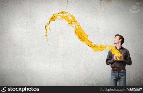 Young man in casual splashing paint from bucket