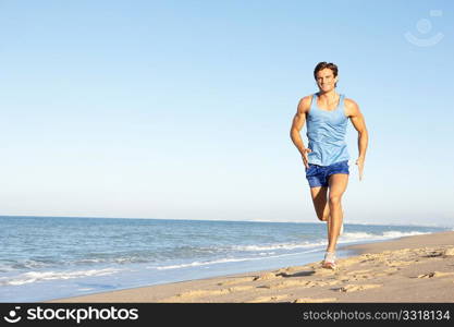 Young Man In Fitness Clothing Running Along Beach