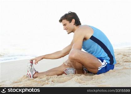 Young Man In Fitness Clothing Stretching On Beach
