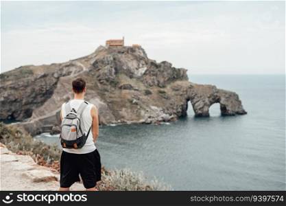 Young man in front of the Gaztelugatxe Island in Vizcaya, Spain