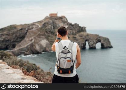 Young man in front of the Gaztelugatxe Island in Vizcaya, Spain