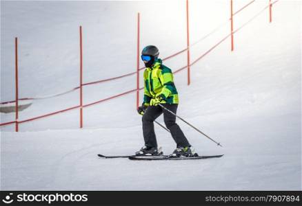 Young man in green suit skiing down the hill