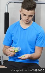 Young Man In Gym Taking Tablets