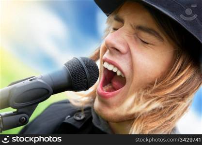 Young man in hat sings to microphone