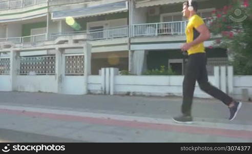 Young man in headphones jogging while listening to music