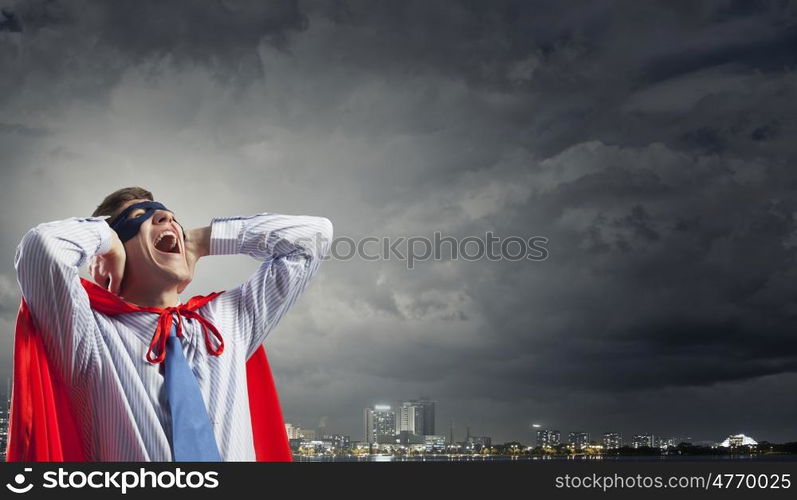 Young man in hero costume closing ears with palms. I need silence