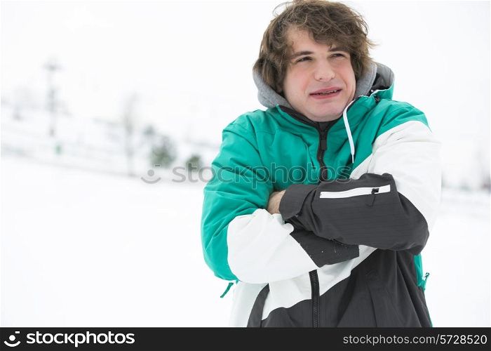 Young man in jacket shivering in snow