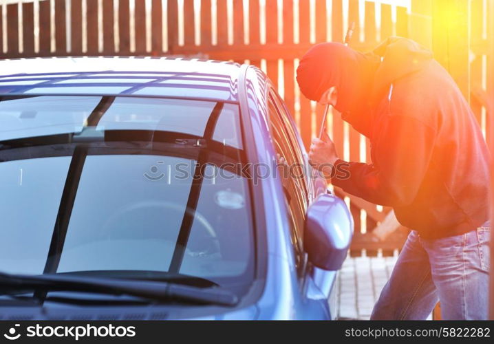 Young man in mask trying to steal a car