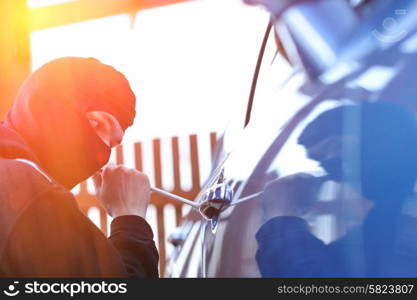 Young man in mask trying to steal a car