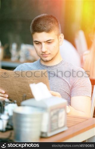 Young man in outdoor restaurant looking at the menu