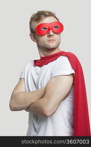 Young man in red superhero costume looking up over gray background