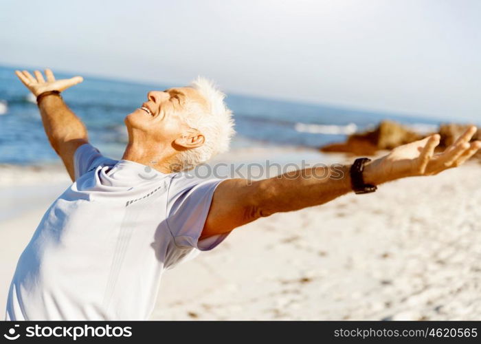 Young man in sport wear with outstretched arms. Young man in sport wear with outstretched arms standing on beach