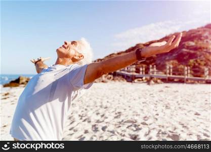 Young man in sport wear with outstretched arms. Young man in sport wear with outstretched arms standing on beach