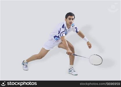 Young man in sports wear playing badminton isolated over gray background