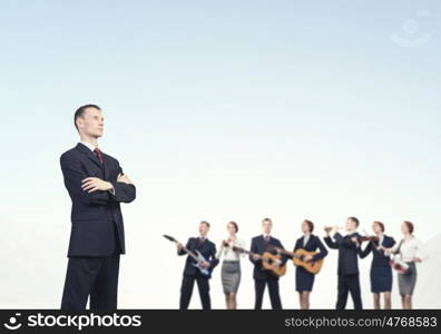 Young man in suit and people playing different music instruments. One man band