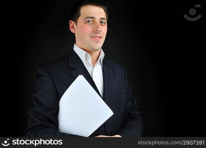 young man in suit with blank paper over dark background