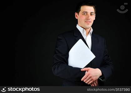 young man in suit with blank paper over dark background