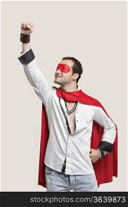 Young man in superhero costume standing against gray background