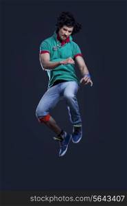 Young man in t-shirt and jeans jumping in air against black background