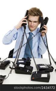 Young man in the office and answering several phones at the same time