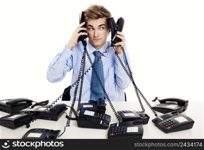 Young man in the office and answering several phones at the same time