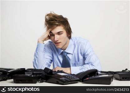 Young man in the office with a bunch of phones on his front