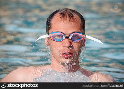 young man in watersport goggles swimming in pool, Aome up from water