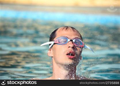 young man in watersport goggles swimming in pool, Aome up from water, taking breath