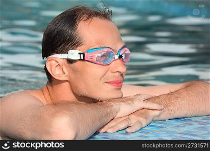young man in watersport goggles swimming in pool, near ledge