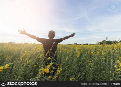 Young man in yellow flower field under beautiful sky