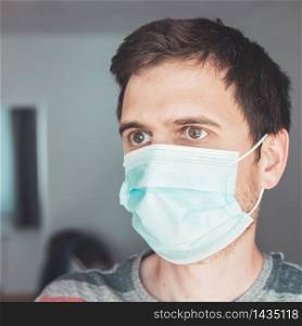 Young man indoor wearing a face mask, portrait. Corona and flu season.