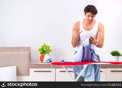 Young man ironing in the bedroom 