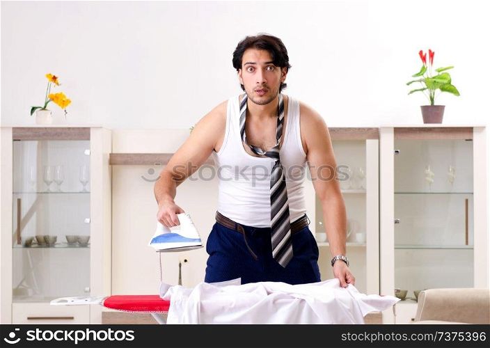 Young man ironing in the bedroom