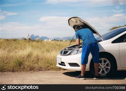 Young man is checking cars on a road in the countryside.
