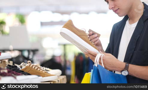 Young man is choosing shoe while doing shopping at the shopping mall.