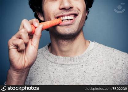 Young man is eating a carrot