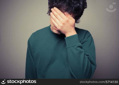 Young man is hiding his face in the palms of his hands