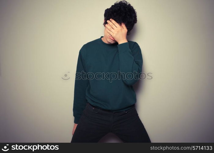 Young man is hiding his face in the palms of his hands