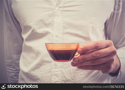 Young man is holding a small cup of coffee
