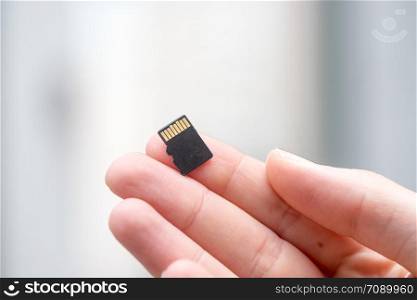 Young man is holding a tiny memory card in his hand, text space