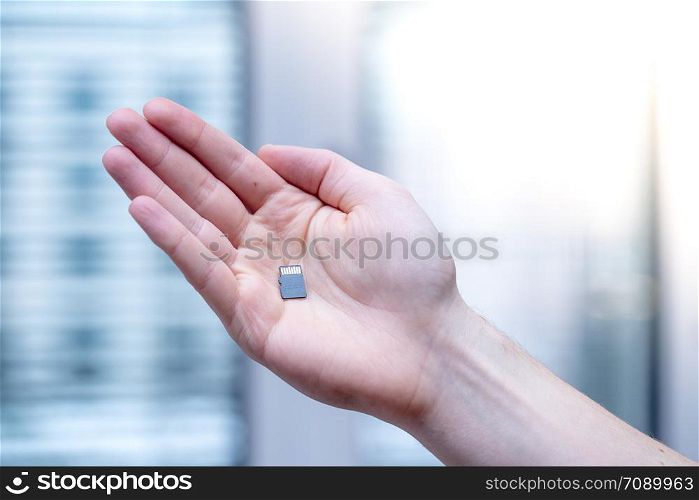 Young man is holding a tiny memory card in his hand, text space