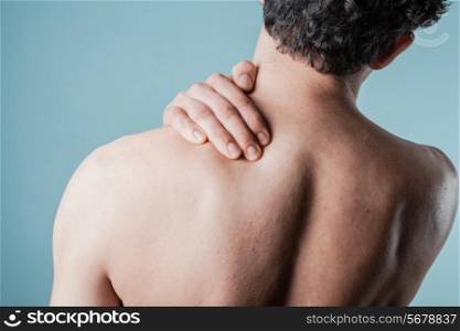 Young man is in pain and is massaging his sore neck