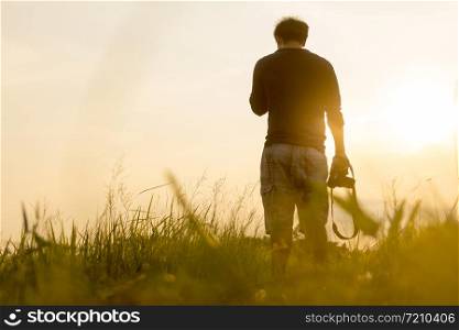 Young man is looking at sunset. Traveller with camera
