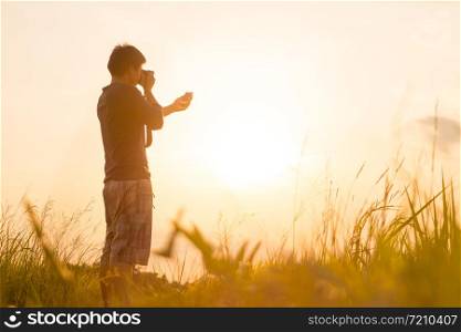 Young man is looking at sunset. Traveller with camera