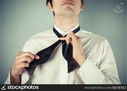 Young man is showing how to tie a formal bow tie