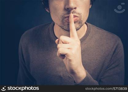 Young man is signalling hush with his finger on his lips
