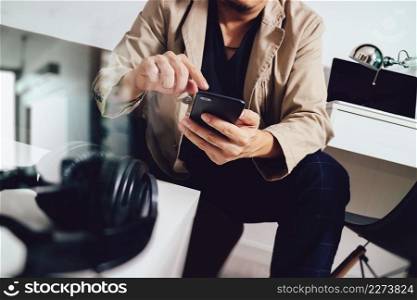 young man is sitting on a sofa shopping on line is listening music with headphones is holding smart phone on his hand at home,omni channel concept,filter