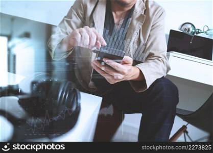 young man is sitting on a sofa shopping on line is listening music with headphones is holding smart phone on his hand at home,omni channel concept,virtual interface computer graphic