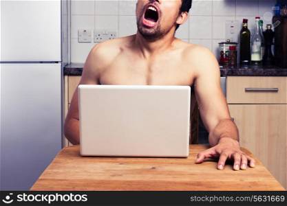 Young man is watching pornography on his laptop in the kitchen